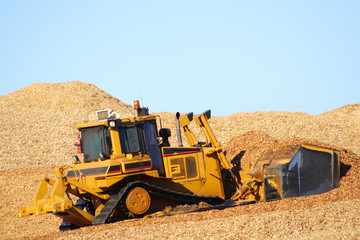 Large earthmover with scoop of wood chips © max blain