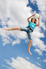 Frau mit einem Ball in ihren Händen springt auf einem Trampolin