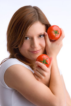 junges, schönes Mädchen in weißem Top hält zwei Tomaten