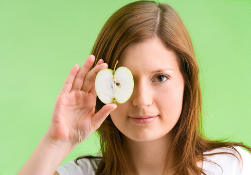 junges, schönes Mädchen hält einen Apfel zu ihrem Auge