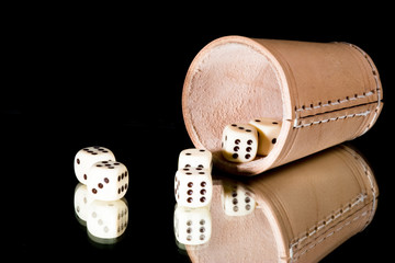 Dice with Dice shaker on a mirror - black background