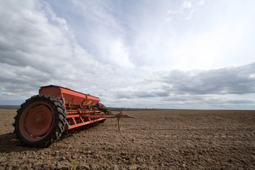 Fototapeta premium Seeding machines at field and sky with clouds.