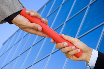 Businessman passing a red baton to another businessman