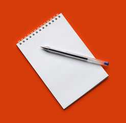 Notebook and pen on the orange background
