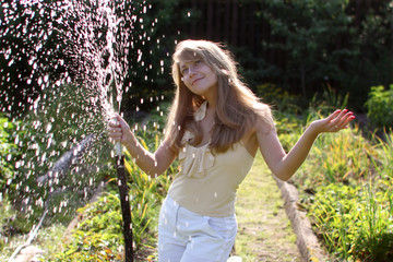 Beautiful girl in the garden with hose