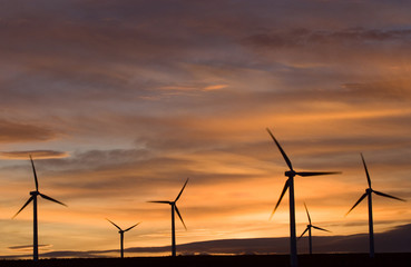 Wind turbines against an orange sunset.