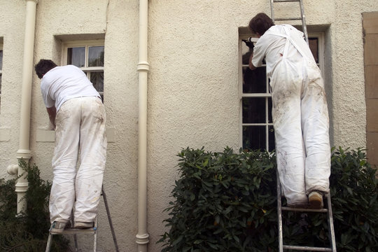 Two painters decorating the exterior of a house.