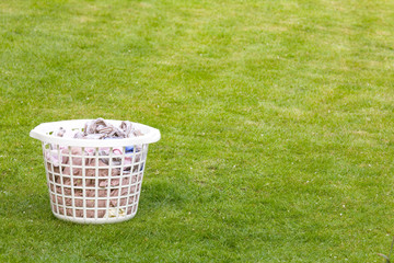 Laundry basket filled with clothes on lawn with copy space