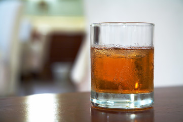 The misted over glass of whisky with an ice on a table