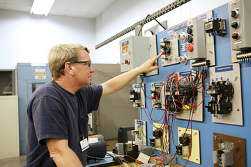 teacher working on an industrial motor control center  - obrazy, fototapety, plakaty