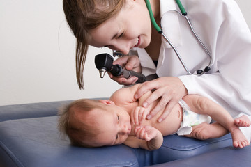 Young female doctor examining a newborn baby.