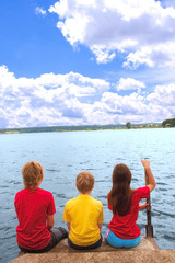 Three children sit on coast