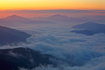 Mountains over the fog in the summer sunrise