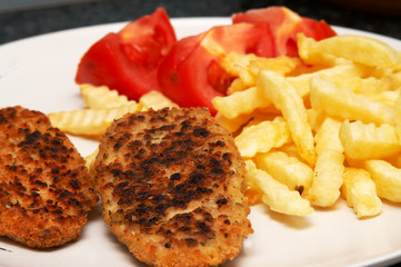 Chicken patties served with chips and sliced tomatoes 