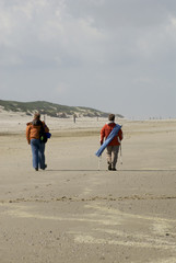 two women are nordic walking on the beach