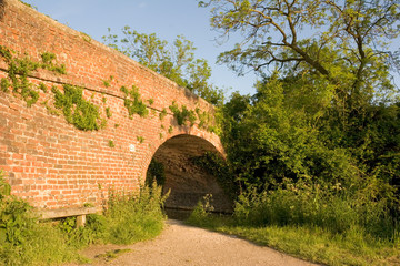 A path leading under a bridge over a canal
