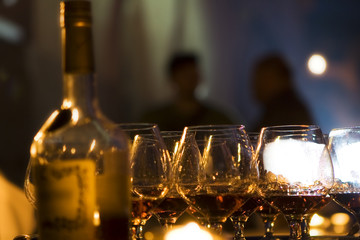 Wineglasses with cognac, a bottle, and evening party outside