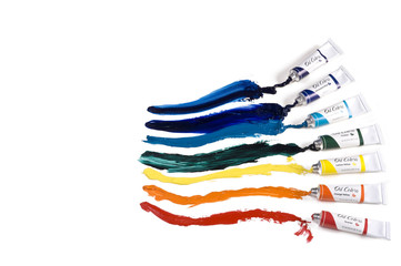 Collection of oil paint tubes with paint spread across paper.