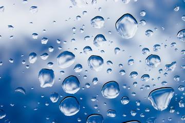 Raindrops on glass with sky on background