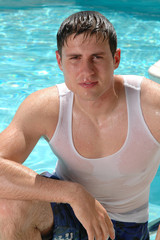 A handsome young man climbing out of the swimming pool