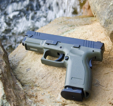 handgun with a waterfall in the background