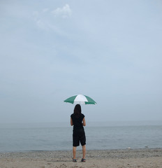 Girl Holding Green and White Umbrella on a Hazy Beach