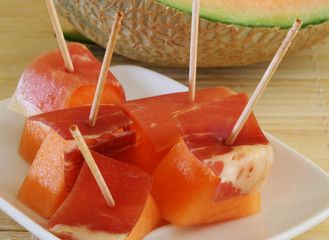 spanish red ham draped over a honeydew melon.