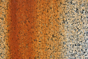 A stone granite wall showing stains created from rusting metal.