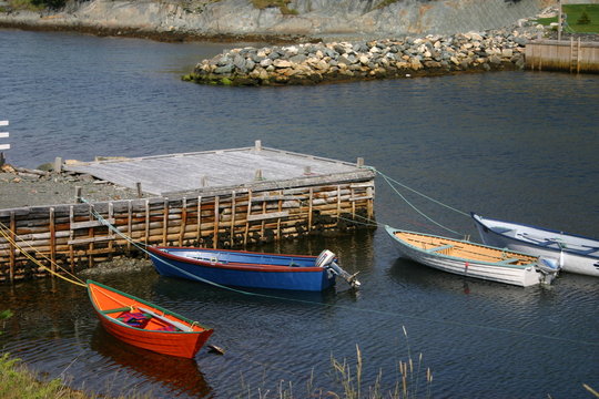 Four boats, one orange at dock