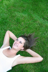 Naklejka na ściany i meble Young woman lying on a lawn 