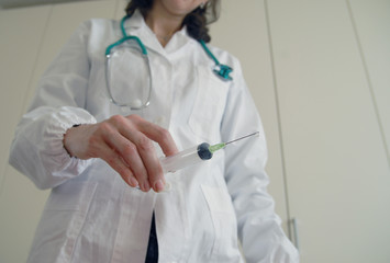 Docator holding with one hand a medical syringe