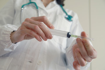 Docator holding with two hands a medical syringe