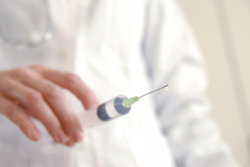 Docator holding with one hand a medical syringe with drop
