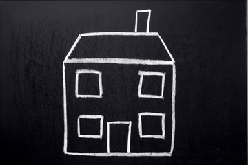 A child’s chalk drawing of a house on a blackboard.