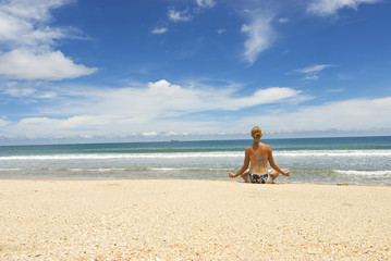 Fototapeta na wymiar attractive young woman sitting in yoga position at the beach