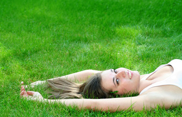 Beautiful young woman lying on a lawn 