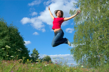 Beautiful lady jumping in summer landscape