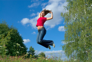 Beautiful lady jumping in summer landscape