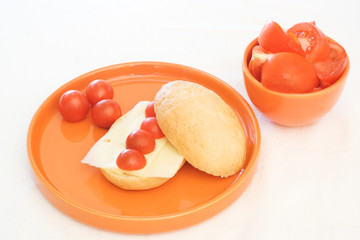 Tomato and cheese breakfast bun on orange plate