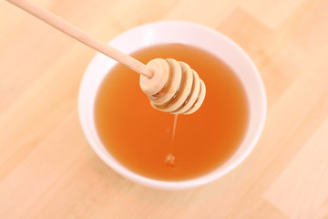 bowl of honey with wooden stick on table