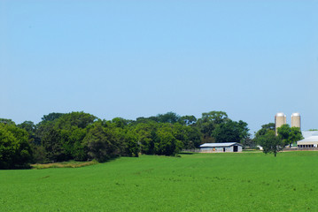 Scenic view of farmland with barns and silos on a sunny day