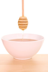 bowl of honey with wooden stick on table