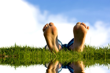 Feets on grass near water.