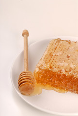 A honeycomb and a honey wand on a plate