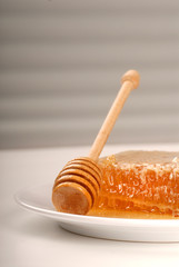 A honeycomb and honey wand on a plate