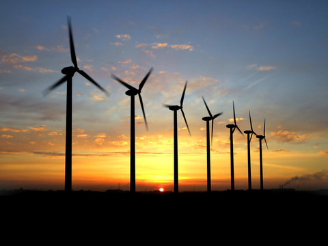 Wind turbine farm over sunset.