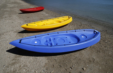 colorful kayaks on beach by turquoise waters