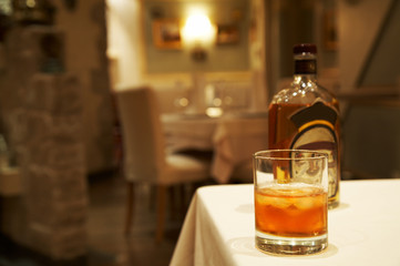 Glass from whisky and a bottle on a table at restaurant