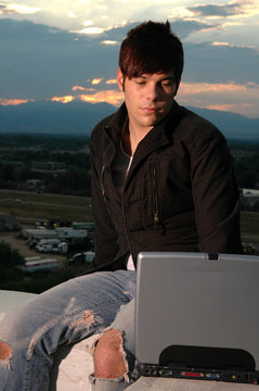 A young man working on his computer outdoors 