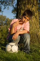 boy shows the peacesign and holds a soccerball
